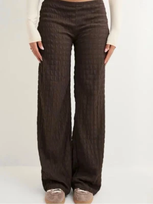 Bruna vida leggings med struktur - Säljer ett par bruna structure pants från Nelly med vid passform och låg midja .