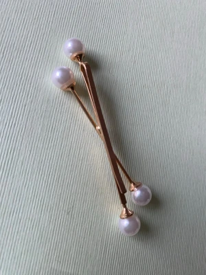 Guldiga hårnålar med pärlor - Två i ett stilrena hårnålar i guldfärgad metall med vita pärlor i ändarna. Perfekta för att ge frisyren en elegant touch. Passar både till uppsatt och utsläppt hår och ger en lyxig känsla till din look.