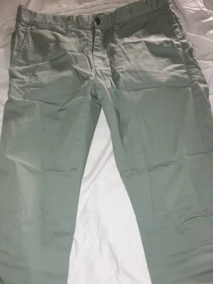 Ljusgröna chinos med raka ben - Snygga ljusgröna chinos med raka ben och klassisk passform. Byxorna har sidofickor och en knappgylf framtill. Perfekta för en avslappnad men ändå stilren look. Tillverkade i ett mjukt och lätt bomullstyg.