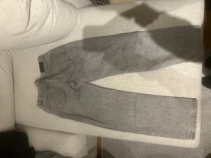 Grå raka jeans från Grunt - Säljer ett par grå jeans från Grunt med rak passform och klassisk femficksdesign. Jeansen har en snygg tvättad look och är tillverkade i denim. Perfekta för dig som gillar en avslappnad och trendig stil.