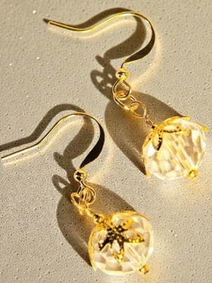 Guldörhängen med kristallpärlor av glas - Snygga örhängen med guldpläterade krokar och detaljer, samt stora, facetterade glaskristallpärlor. Pärlorna har dekorativa guldfärgade metallhattar som ger en elegant och unik look. Perfekta för dig som vill sticka ut med stilrena accessoarer.