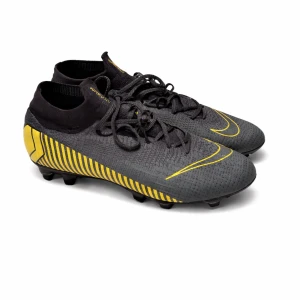 Nike Mercurial grå/gula fotbollsskor - Snygga Nike Mercurial Superfly 6 Elite SG-Pro Anti-Clog fotbollsskor i grått med gula detaljer och svart sula. Skorna har strumpliknande skaft, snörning och mönstrad ovandel i syntetmaterial, SG-Pro dobbar. Skorna säljs inte längre och är sällsynta och väldigt eftertraktade. Dem är endast använda 2 gånger och är i dunder skick. Priset är ej hugget i sten och kan sänkas vid snabb affär. Vid minsta fundering är det bara att höra av sig!