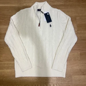 Ralph Lauren Quarter Zip - Säljer en helt ny quarter zip från Ralph Lauren i vit färg med svart broderad logga på bröstet. ✔ Helt ny / oanvänd ✔ 100% bomull ✔ Klassisk och tidlös modell ✔ Svart broderad logga framtill ✔ Bekväm passform ✔ Skickas säkert och välpackad Endast seriösa köpare tack. Skriv vid intresse eller frågor 😊