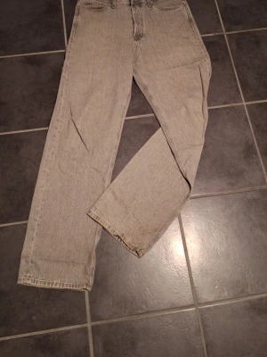 Ljusgråa baggy jeans - Säljer ett par Jack & Jones Alex baggy jeans i bra skick (längst ner är det mer använt eftersom de har hängt ner på marken) Riktigt skön modell med lös passform och bra fall över skorna. Passar perfekt till hoodie, zip eller t-shirt för en avslappnad stil.