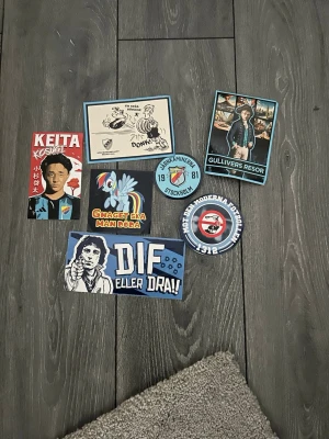 Samling Djurgården klistermärken - Säljer en samling klistermärken med Djurgården-tema. Motiven inkluderar spelare, klubbmärken, slogans och illustrationer i blått, vitt och rött. Perfekt för att dekorera laptop, mobil eller andra ytor med DIF-support.