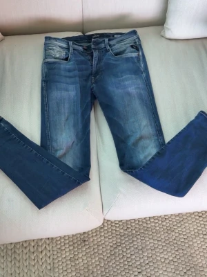 Blå Replay Anbass slim fit jeans med slitningar - Säljer ett par blå slim fit hyperflex jeans med snygga slitningar och tvättade detaljer. Jeansen har klassisk femficksmodell och smala ben. Storlek W31 L32. Hjärtat på bild två är bara vatten.