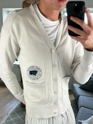 Cardigan Vit Tommy Hilfiger  - Väldigt stilren och extremt schysst cardigan med en snygg loga! Färg: vit/beige. Mått: A:52 B:42 C:42 D:63 (cm) Skriv vid fundering!😇🙌