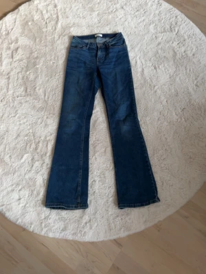 Mörkblå bootcut jeans - Snygga mörkblå bootcut jeans med klassisk femficksdesign och normalhög midja. Jeansen har utsvängda ben och är tillverkade i ett mjukt denimtyg som ger en skön passform. 