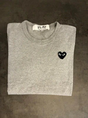Grå t-shirt Comme des Garçons Play - Snygg grå t-shirt från Comme des Garçons. Storlek m men små i storleken. Perfekt nu under sommaren☀️