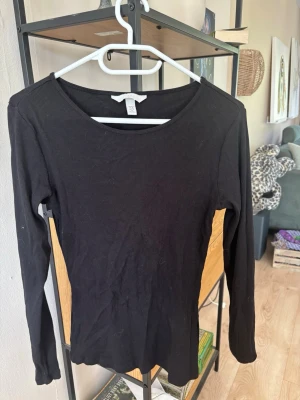 Svart ribbad långärmad topp H&M - En svart, ribbad långärmad topp från H&M. Toppen har rund halsringning och är figurnära i modellen, perfekt att styla med jeans eller kjol. Tillverkad i mjukt material som känns skönt mot huden.