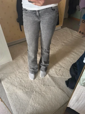 H&M lågmidjade bootcut jeans - Ett par gråa lågmidjade bootcut jeans i storlek 34/XS men passar mer 36/S för dem har blivit mer stretchiga från H&M.  Köpt från någon annan på vinted därav säljer jag dom för dom passar inte  Midjemått: 38cm Grenhöjd: 20cm Innerbenslängd: 81cm