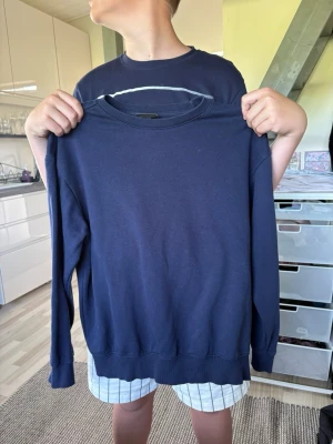 Mörkblå sweatshirt från H&M ! - En enkel och stilren mörkblå sweatshirt från H&M i relaxed fit. Tröjan har rund halsringning, långa ärmar och ribbade muddar vid ärmslut och nederkant. Perfekt för en avslappnad look och lätt att matcha med andra plagg.