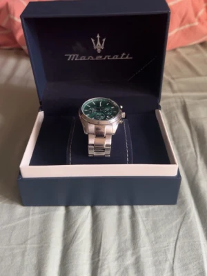 Maserati klocka med grön urtavla - Stilren klocka från Maserati med grön urtavla och silverfärgad länk i metall. Klockan levereras i originalbox och har klassisk rund form med detaljerad urtavla och Maserati-logga. Perfekt accessoar för dig som gillar snygga detaljer.
