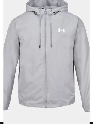 Ljusgrå vindjacka från Under Armour - Snygg ljusgrå vindjacka från Under Armour med dragkedja framtill, justerbar huva och logga på bröstet. Jackan har långa ärmar och är tillverkad i ett lätt och smidigt material som passar perfekt för blåsiga dagar.
