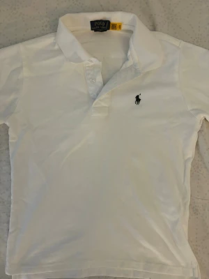 Vit Ralph Lauren piké - Vit piké ifrån Polo Ralph Lauren. Storlek S, sitter som XS. Köpte begagnad är för liten för mig. Skick - Mycket bra!✅ Priset går att diskutera, skriv för frågor eller prisförslag!