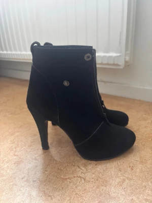 Amati svarta ankelboots i äkta läder – stl 37 - Eleganta svarta ankelboots från Amati i äkta läder. Klassisk modell med hög klack och dragkedja. Fint begagnat skick. Storlek 37.