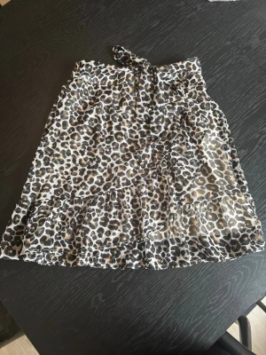Leopardmönstrad kortkjol med volang - Säljer en kjol med leopardmönster och volangkant. Kjolen har omlottmodell och knyt i midjan. 