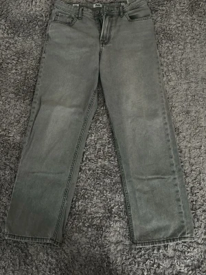 Grå ljus från Jack Jones  - Snygga grå jeans från H&M med rak passform och klassisk femficksdesign. Jeansen har en tvättad look och är tillverkade i denim. Perfekta för dig som gillar en avslappnad stil och vill ha ett par stilrena basjeans.
