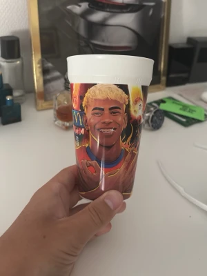 Lamine yamal  - Cool plastmugg från McDonald's med färgglad illustration av en fotbollsspelare och texten 'Lamine Yamal'. Muggen har vit topp och motiv i rött, gult och blått. Perfekt för samlare eller som unik dryckesbägare.