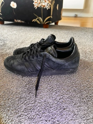 Adidas gazelle - Tjena, jag säljer dessa svarta Adidas Gazelle. Ingenting är fel på dom, dock har materialet börjat blekna. Men om du har rätt verktyg går det enkelt att lösa.  Storlek 42 2/3  Skriv om du undrar något!