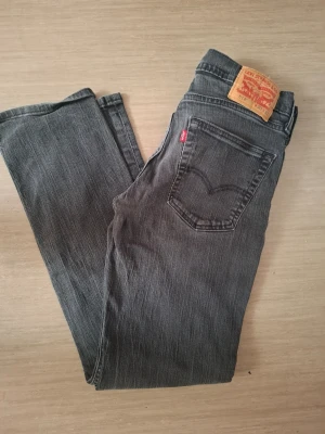 Svarta Levi's 511 slim jeans - Säljer ett par svarta Levi's 511 slim jeans med klassisk femficksmodell och knappgylf. Jeansen har en något tvättad look och är tillverkade i denim med stretch för extra komfort. Passar perfekt till en avslappnad och trendig stil.