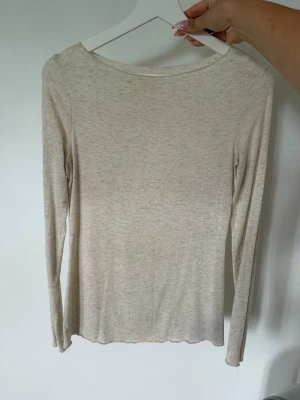 Intimissimi Beige långärmad topp i bomull - En stilren och enkel beige långärmad topp med rund halsringning. Tillverkad i mjuk bomull som känns skön mot huden. Perfekt att matcha med jeans eller kjol för en avslappnad look.