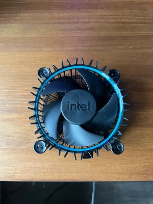 Intel Core CPU-kylare med applicerad kylpasta - En svart rund CPU-kylare från Intel med inbyggd fläkt och kylflänsar i metall. Botten har en kopparplatta för effektiv värmeavledning. Monteras enkelt med push-pins och passar till stationära datorer.