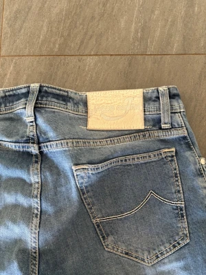 Ljusblå Jacob Cohën jeans - Snygga ljusblå jeans från Jacob Cohën med raka ben. Jeansen har en ljus tvätt och tydliga sömmar på bakfickorna samt ett vitt läderpatch med logga bak i midjan. Perfekta för en avslappnad och trendig look och de som även vill sticka ut. Priset går att diskutera vid snabb affär 😊