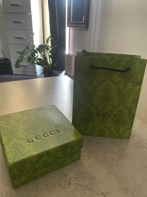 Gucci bälte med silverdetaljer - Säljer ett exklusivt Gucci bälte med klassisk design och silverfärgat spänne. Bältet levereras i original grön Gucci-box och påse, perfekt för dig som vill ha något lyxigt och tidlöst från ett av världens största modehus.