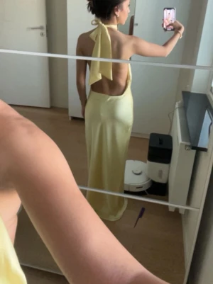 Ljusgul långklänning med öppen rygg - Säljer en elegant ljusgul långklänning med halterneck och knytning i nacken. Klänningen har öppen rygg. Använd en gång av mig, köpte den ny på Vinted med lapp kvar. Inga skador alls.