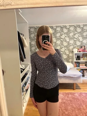 Blommig långärmad topp - Mörkblå långärmad topp från Kappahl  med små gröna blommor över hela tyget. Toppen har v-ringning och är figurnära i modellen. Perfekt att matcha med jeans eller kjol för en snygg vardagslook. Storlek 158/164 för barn men fyller i annat som INTE stämmer eftersom man inte kan fylla i barnstorlekar
