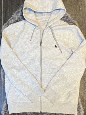 Polo Ralph Lauren Zip Hoodie - Grå zip hoodie från Ralph Lauren i storlek M. Mycket fint skick och sparsamt använd. Klassisk och stilren modell som funkar perfekt till vardags.