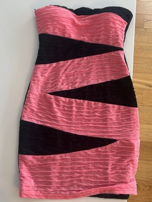 Rosa och svart axelbandslös klänning - Axelbandslös kort klänning i rosa och svart , med inbyggda inlägg som man bara kan ta ut om man vill, klänningen är kort och tajt 💕