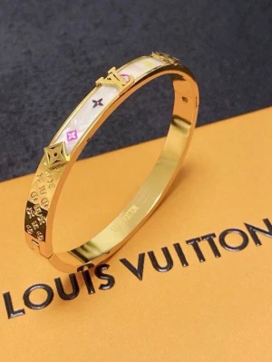 Louis Vuitton guldigt armband - Snyggt armband från Louis Vuitton i guldfärgad metall med vita och rosa detaljer samt klassiska LV-loggor och monogram. Armbandet har en stilren, rund form och är dekorerat med små stjärnor och blommor i relief. Perfekt accessoar för att lyfta din outfit.