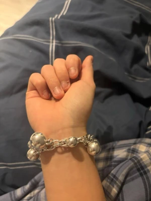 Silverfärgat armband med stora pärlor - Säljer ett chunky armband i silverfärg med stora, blanka pärlor och en länkdesign. Armbandet har även en rund bricka med ingraverad text och ett coolt spänne. Perfekt för dig som gillar statement-smycken och vill sticka ut prec empiriskt.