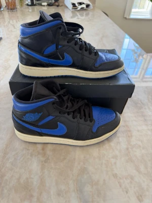 Air Jordan 1 mid Royal blue  - Säljer ett par Air Jordan 1 färgen Royal blue👟. Skorna har svart och blått läder, klassisk Nike logga på sidan och Air Jordan-logga vid ankeln. Tjock vit sula och svarta skosnören. Lådan ingår i köp🔥📦