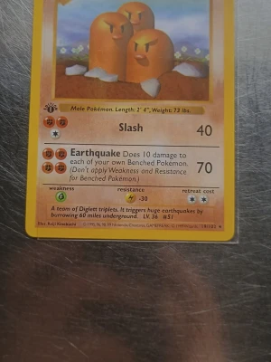 Pokémonkort Dugtrio 1st Edition  - Säljer ett original Pokémonkort från Base Set med Dugtrio (#19/102). Kortet har gul ram, motiv av tre bruna mullvadar och klassiska Pokémonbaksidan. Perfekt för samlare eller nostalgiker som gillar Pokémonkort.