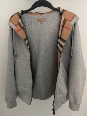 Grå hoodie från Burberry med mönstrad huva - Mjuk och varm burberry hoodie. Använd under 5 gånger.                                                          Skick 9/10