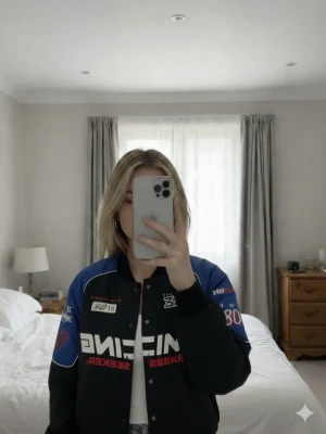 Racing bomberjacka med tryck - Säljer en svart och blå bomberjacka med racing-inspirerade tryck och brodyr. Jackan har ribbade muddar, tryckknappar och coola detaljer som siffror, flaggor och texten 'RACING THRILL SEEKER'. Materialet är syntet och jackan har en loose passform.