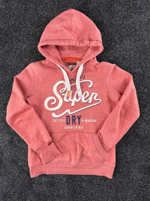 Röd/rosa vintage hoodie från Superdry - Röd/rosa vintage hoodie från Superdry. Väldigt eftertraktad. Fint skick. Storlek small, men passar även xs. Vid frågor är det bara att höra av sig. 