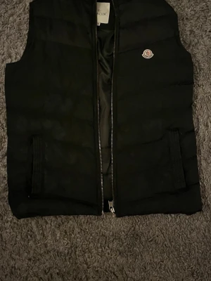 Moncler väst  - Säljer denna Moncler västen, priset är billigt då dragkedjan är paj! Den går att laga hos någon som kan men har inte tiden! Hör av er🅱️
