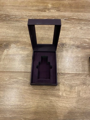 Lila parfymask från Lattafa Amethyst - Säljer en elegant lila parfymask från Lattafa Amethyst Badee Al Oud. Asken har en lyxig känsla med fönster i locket och plats för en parfymflaska. Perfekt för att förvara eller ge bort din favoritdoft.