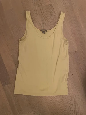 Gul linnetopp från Åhléns - Snygg gul linnetopp från Åhléns med klassisk rund halsringning och ärmlös design. Perfekt att matcha med jeans eller kjol för en gullig liten sommer outfit!! Tillverkad i mjuk bomull som känns skön mot huden.💛💛