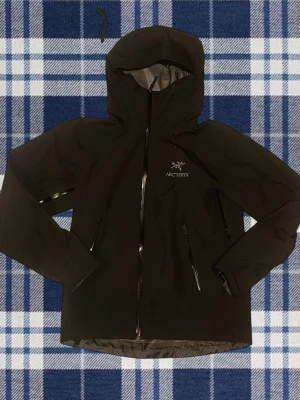  Arc'teryx Beta LT - Svart regnjacka från Arc'teryx med huva och vattentäta dragkedjor. Jackan är goretex vilket betyder att vattnet inte fastnar på jackan vilket gör att det blir väldigt torrt innanför vid regn. Använd några få gånger. Nyskick. Storlek Small 