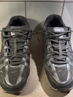 Nike svarta mesh sneakers - Säljer ett par svarta Nike sneakers med mesh- och syntetpaneler. Skorna har en sportig look med tydliga swoosh-loggor på sidan och reflekterande detaljer. Klassisk snörning och vadderad plös för extra komfort.