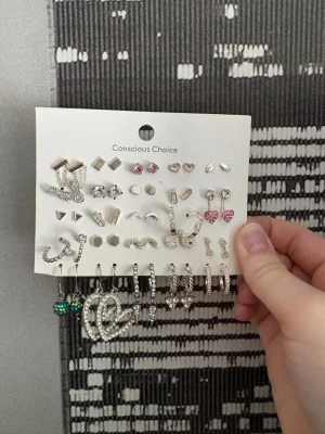 Set med örhängen från Conscious Choice - Säljer ett stort set med örhängen i olika former och stilar. Setet innehåller både studs och hängande örhängen i silverfärg. Alla har bakstycken🤗 De flesta i bra skick och de är köpta från olika butiker så vet ej var de riktigt är ifrån🥰
