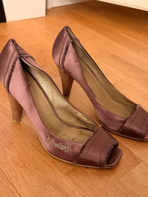 Bruna  satin-pumps från Replay - Säljer ett par bruna pumps från Replay i satinmaterial med öppen tå och träklack. Storlek 36