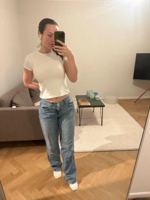 Low wide jeans från Gina tricot  - Säljer ett par klassiska blå jeans från Gina med rak passform och låg midja. Jeansen har fem fickor, knappgylf och är tillverkade i slitstarkt denim. Perfekta för en avslappnad och cool look.