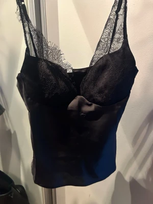 Svart festopp med tunna axelband - Snygg svart festopp med tunna axelband och detaljer i spets. Storlek M men passar även storlek S