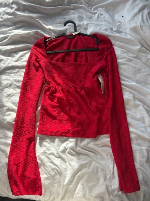 Långärmad topp - Röd finare tröja från Nelly, aldrig använd därav prislappen på. I storlek xs men skulle säga att den passar både xs och s med!